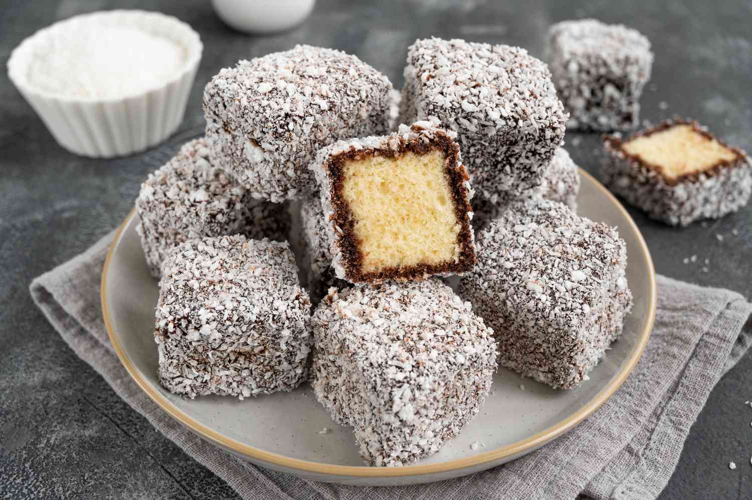 A plate of assorted Lamingtons, including classic, chocolate, and lemon variations, beautifully arranged for a tea party.