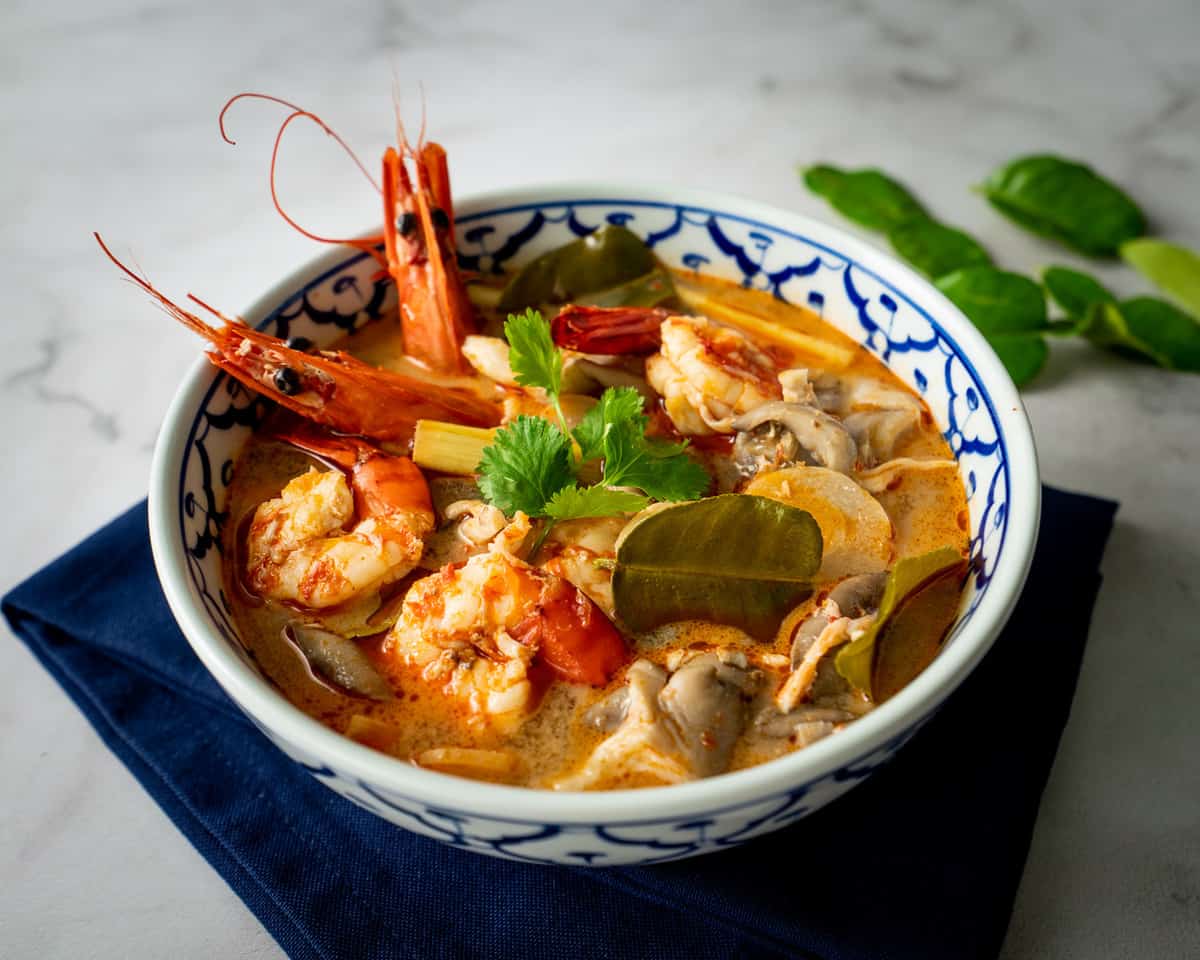 Semangkuk Tom Yum yang segar dan pedas, dengan udang besar, jamur, dan rempah segar, siap untuk dinikmati