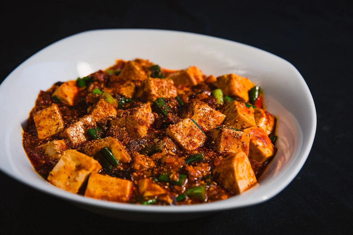 Close-up of Ma Po Tofu with a rich, spicy sauce and scallions 