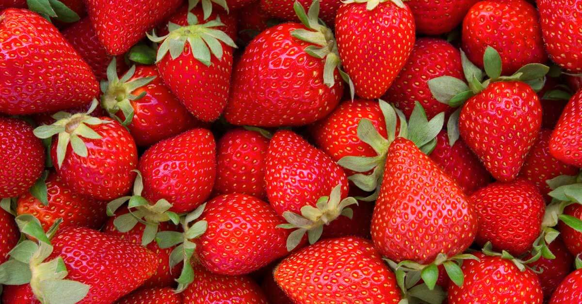 A vibrant salad topped with sliced strawberries and nuts. 