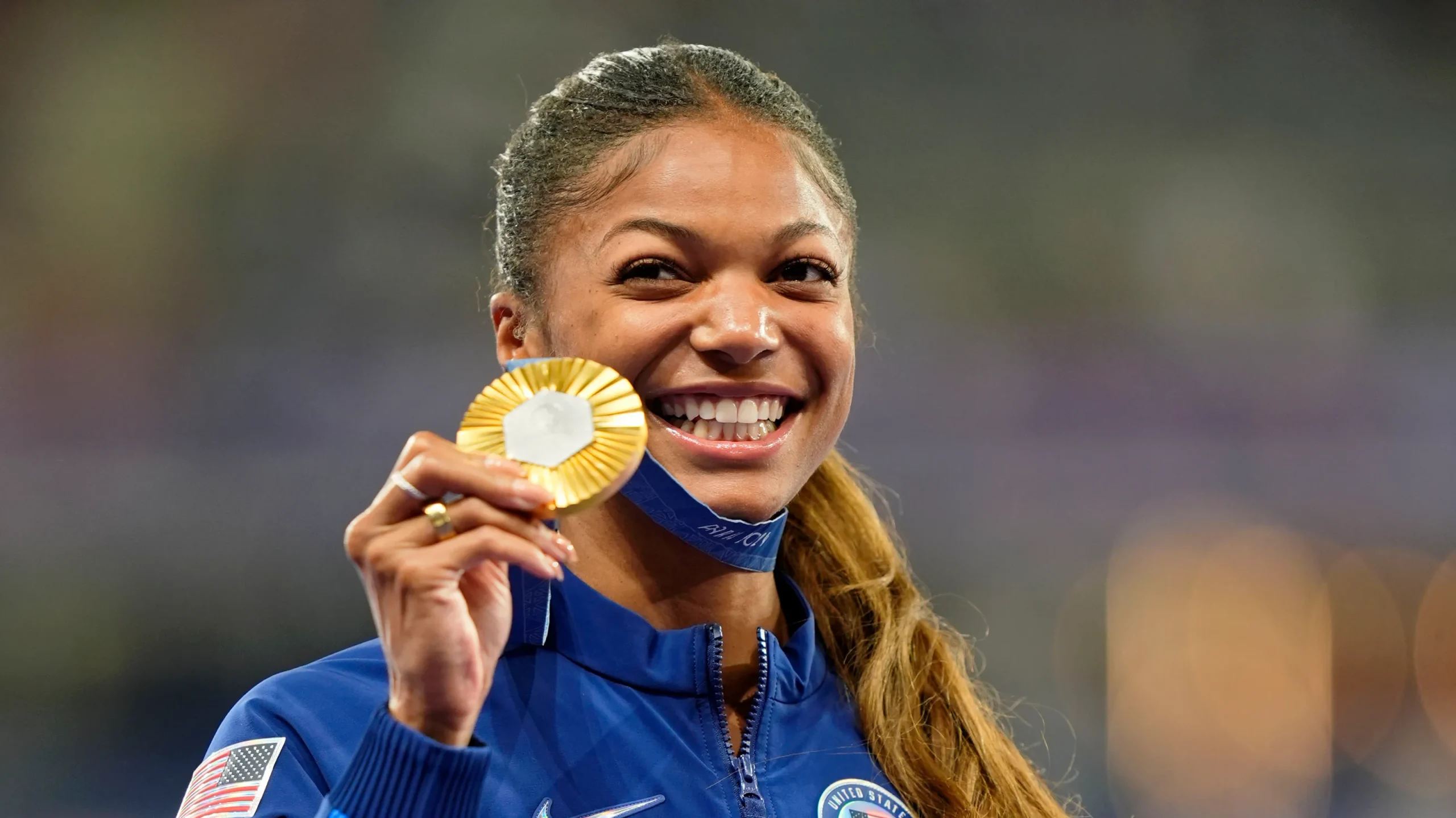 French track and field star crossing the finish line at Paris 2024. 