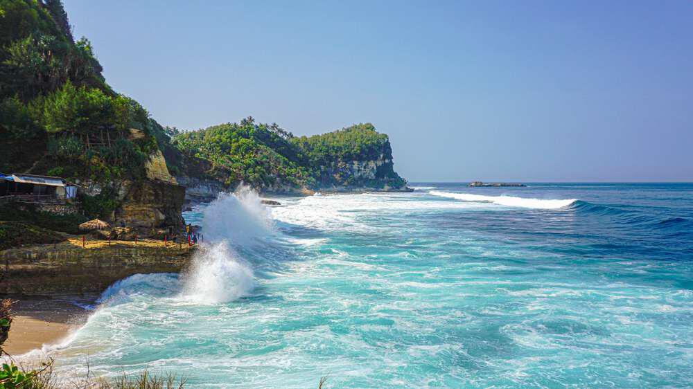 Keindahan air terjun di Pantai Banyu Tibo yang mengalir langsung ke laut biru jernih, menciptakan pemandangan yang memukau