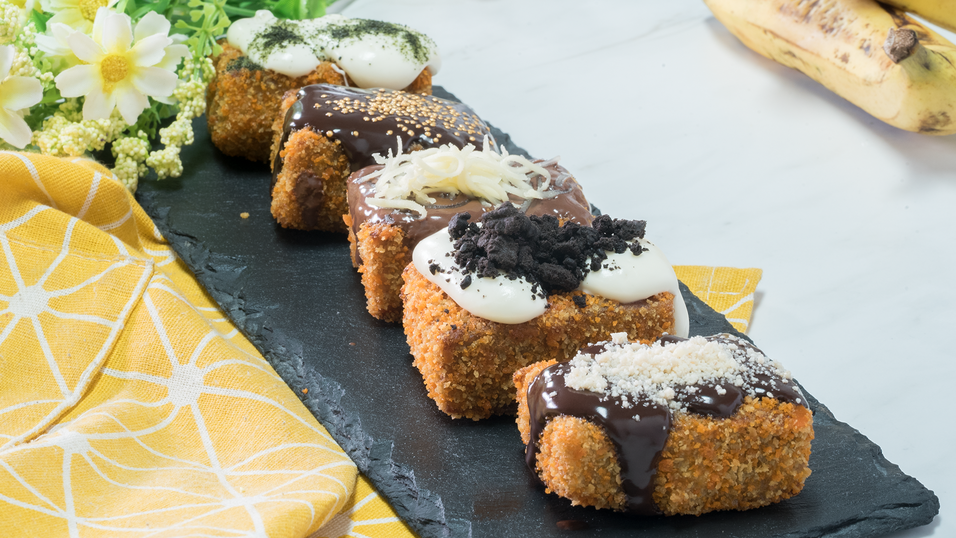 Pisang Nugget Renyah: Potongan pisang nugget yang renyah di luar dan lembut di dalam, disajikan dengan topping cokelat leleh yang menggoda