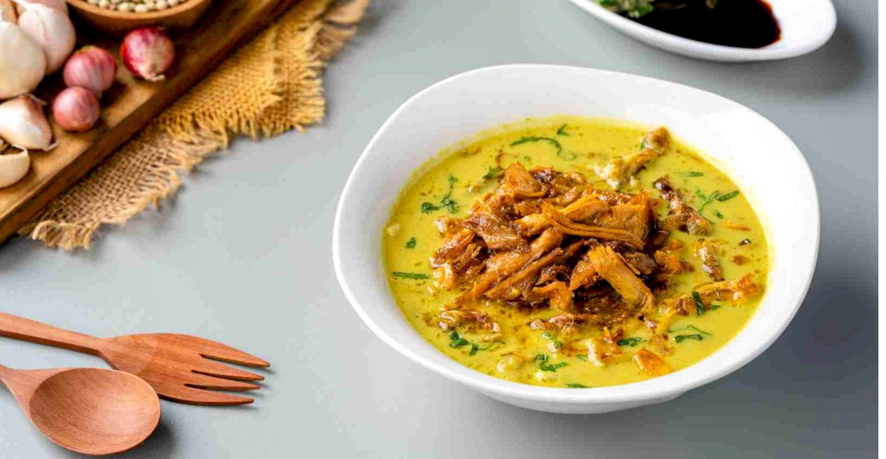 Semangkuk bihun soto Medan dengan kuah santan kental, lengkap dengan potongan ayam dan taburan bawang goreng.