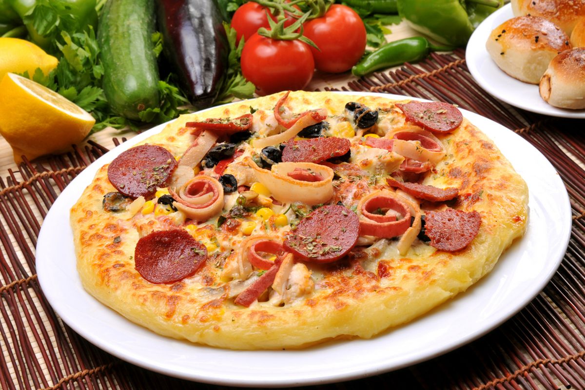 Sepotong pizza sosis yang menggugah selera, dilengkapi dengan lelehan keju mozzarella dan saus tomat segar